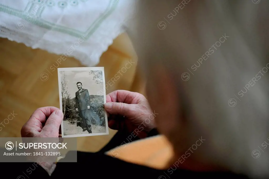 Senior woman is looking at an old photography.