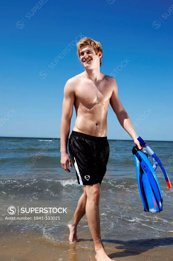 Portrait of a young blonde man with fins at the sea.