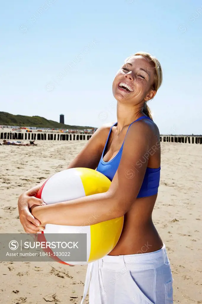 Portrait of a young blonde woman playing ball on the beach.