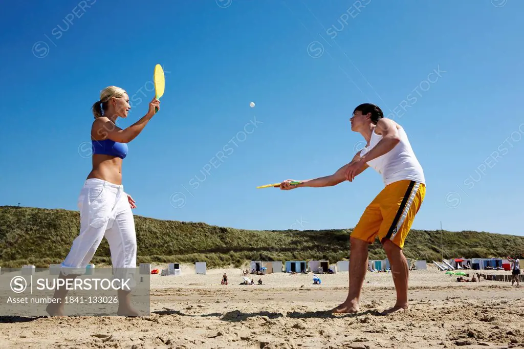Young man and young woman are playing beachball on the beach.