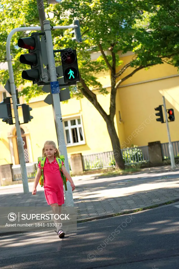 Girl is crossing the road when the ligh shows green.