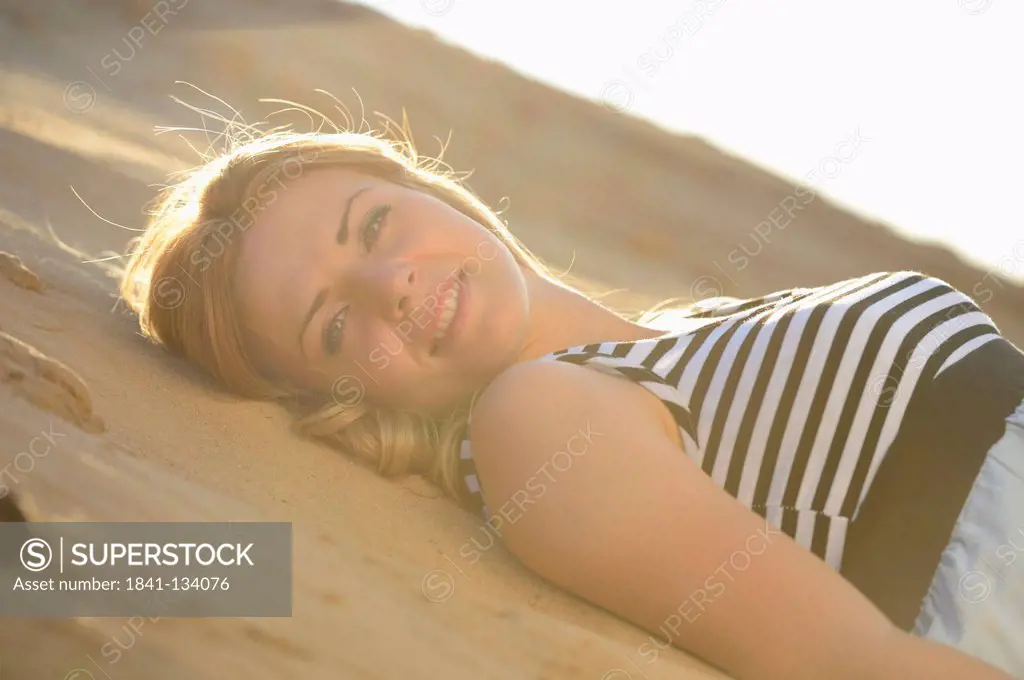 Young woman wearing dress lying on beach