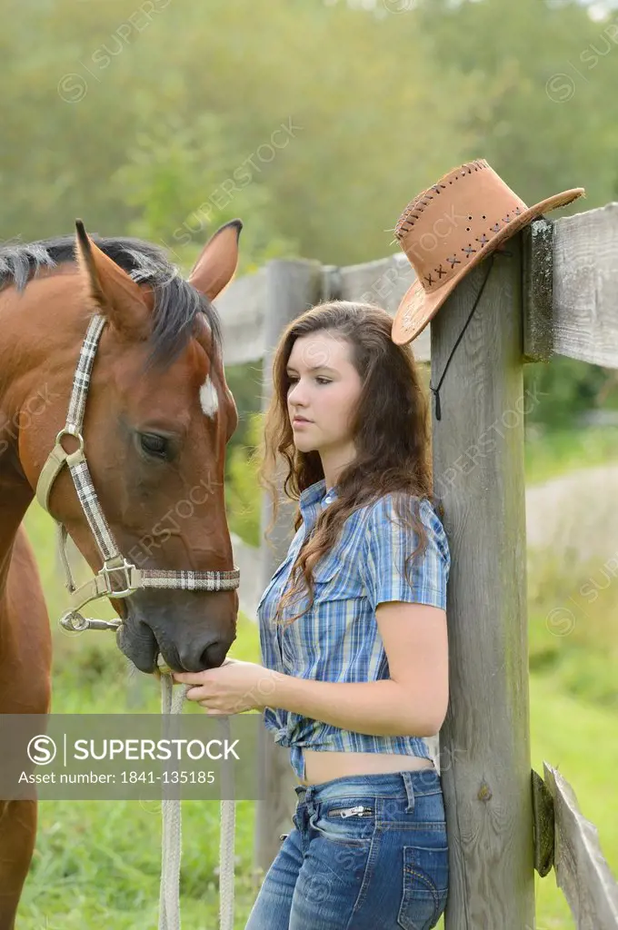 Teenage girl standing with a Mecklenburger horse on a paddock