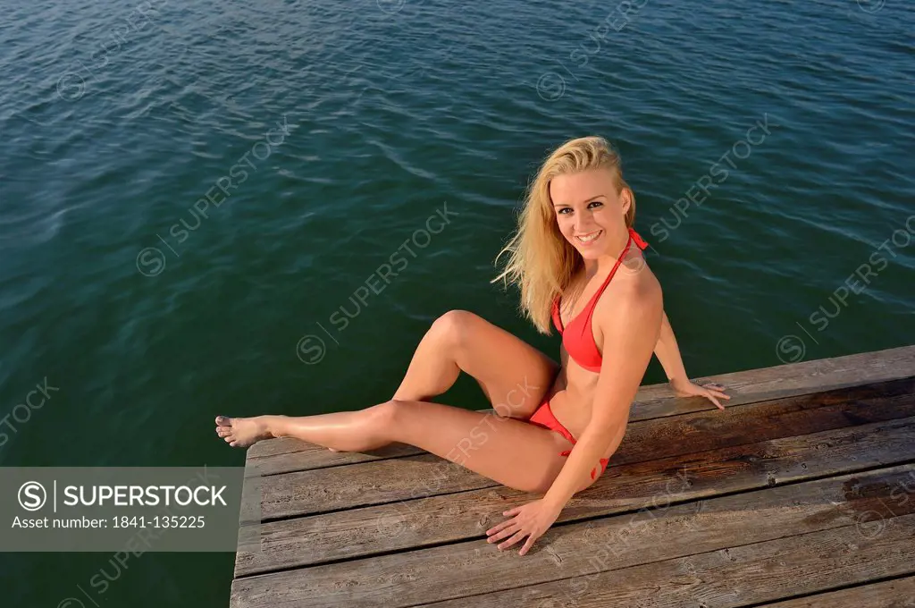 Young blond woman in bikini on a jetty at a lake, Styria, Austria