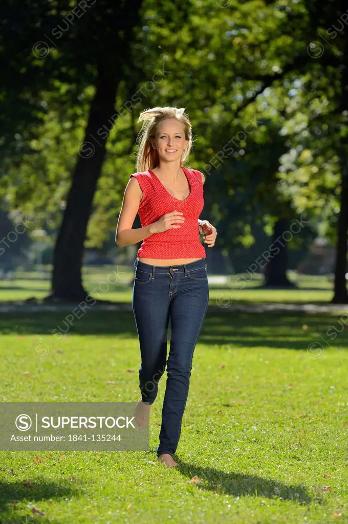 Young blond woman running in a park