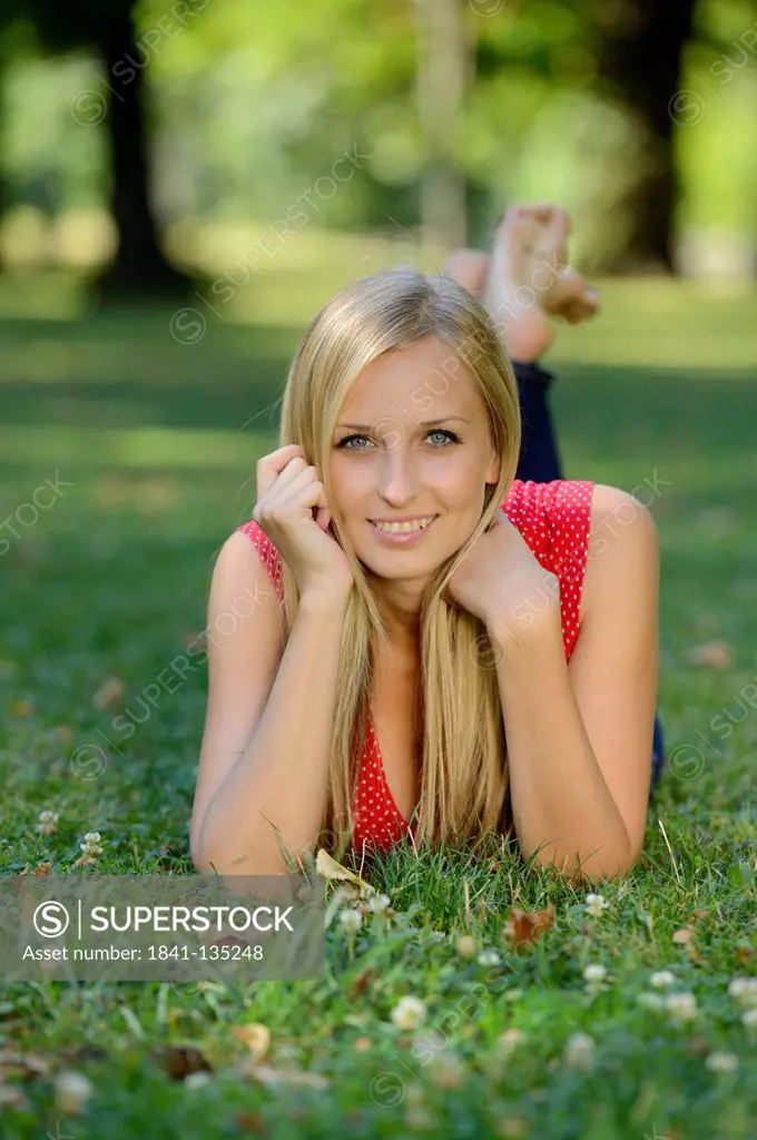 Young blond woman lying in a park