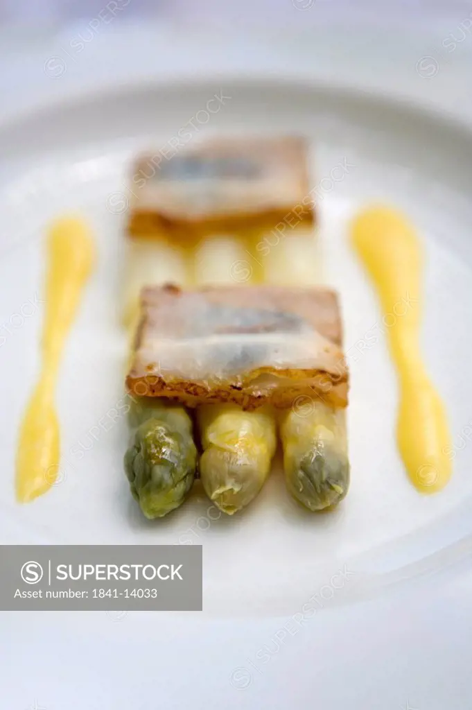 Close_up of crackers and asparagus with mustard sauce on plate