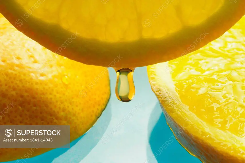 Close_up of drop of lemon juice dripping from slice of lemon
