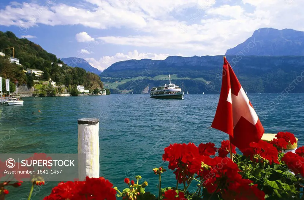 Flowers with Swiss flag on coast with ship in background, Switzerland