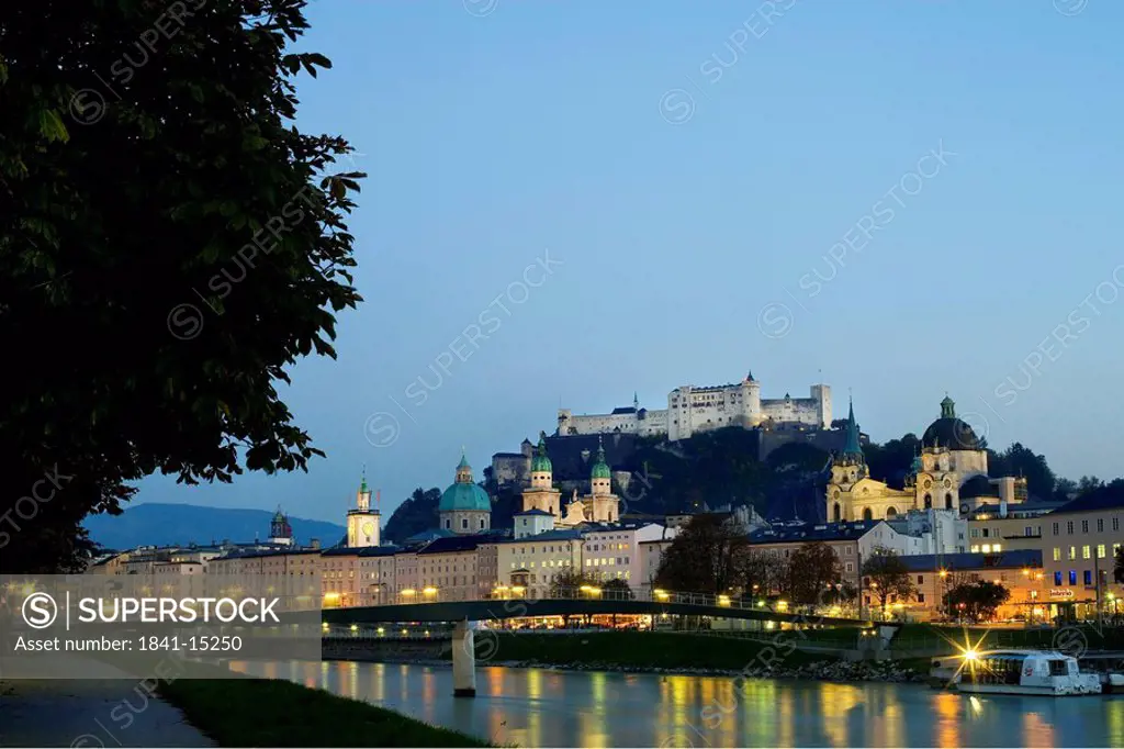 Buildings on waterfront with castle in background, Salzach River, Burg Hohenwerfen Castle, Salzburg, Austria