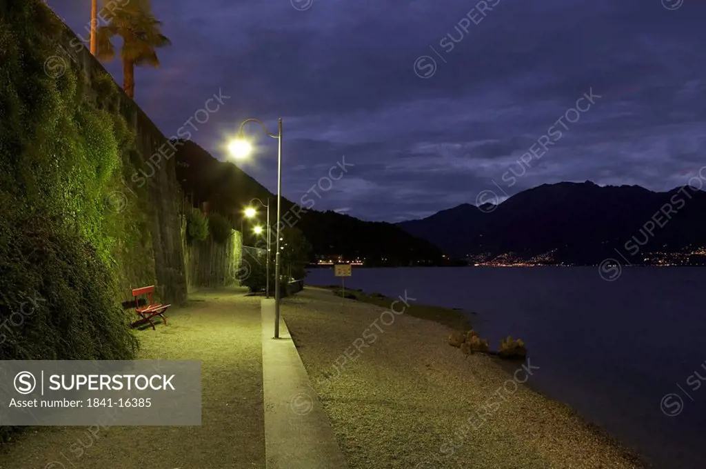 Empty bench near lit up lampposts at lakeside, Lake Maggiore, Switzerland