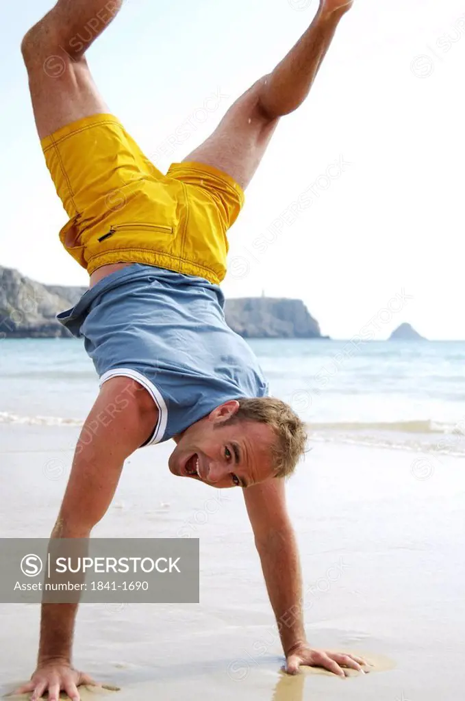 Man doing handstand at beach