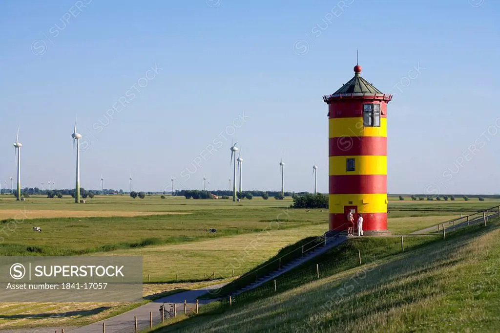 Two people standing in front of lighthouse, Pilsum, Lower Saxony, Germany