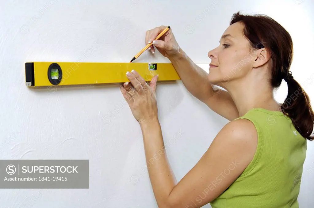 Close_up of woman using spirit level to mark wall