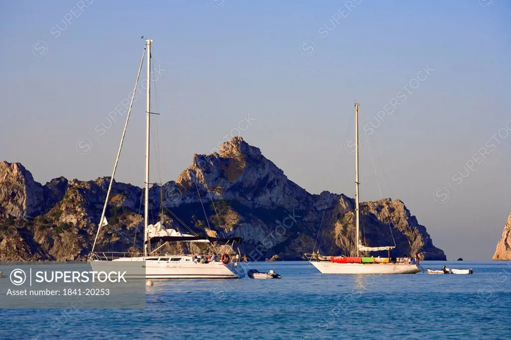 Sailing yachts in front of a rocky island Es Vedra, Ibiza, Spain