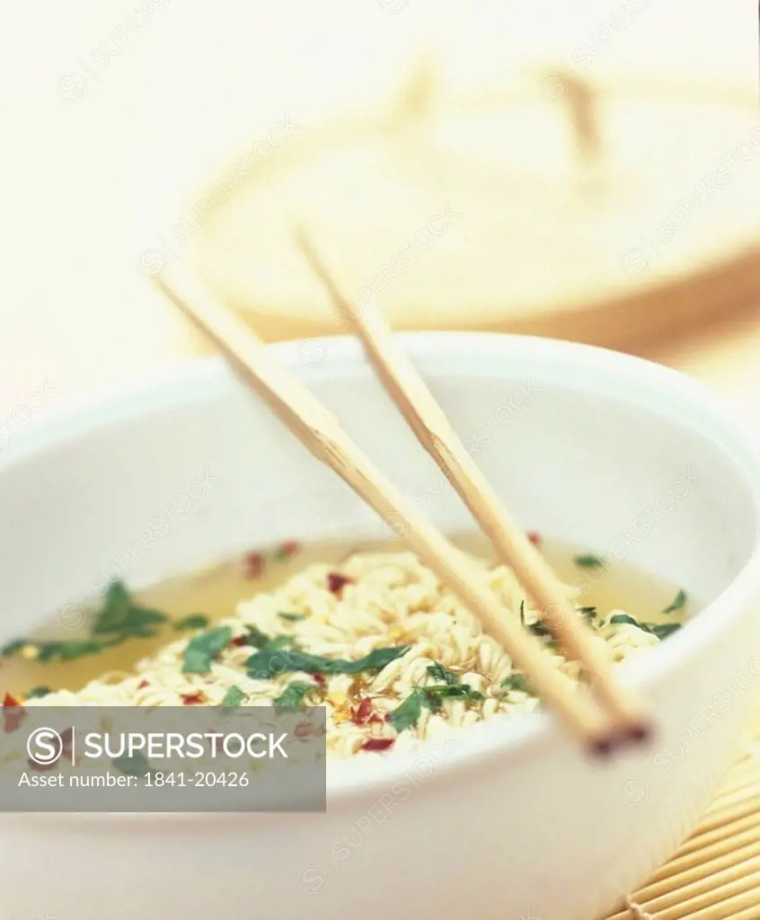 Close_up of a dish of noodle soup with chopsticks