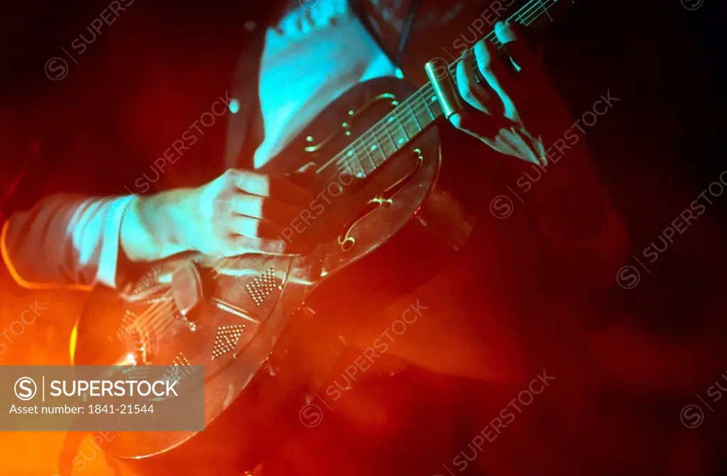 Mid section view of man playing guitar on stage