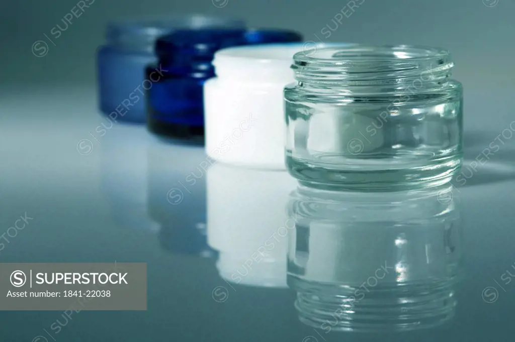 Four cream jars in a row, close_up