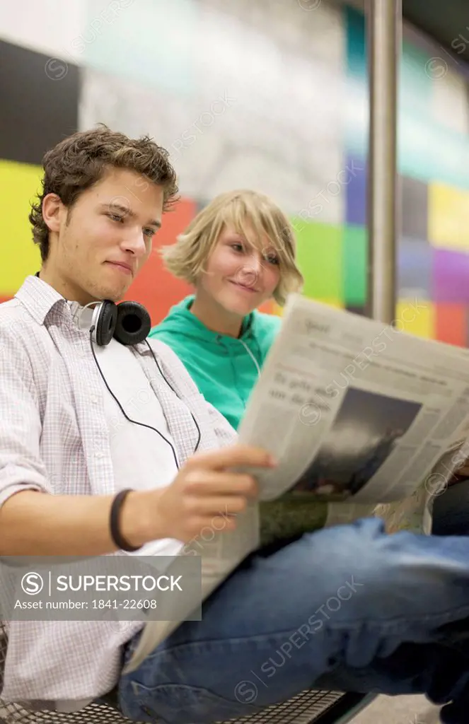 Teenager couple readung newspaper at underground, low_angle view