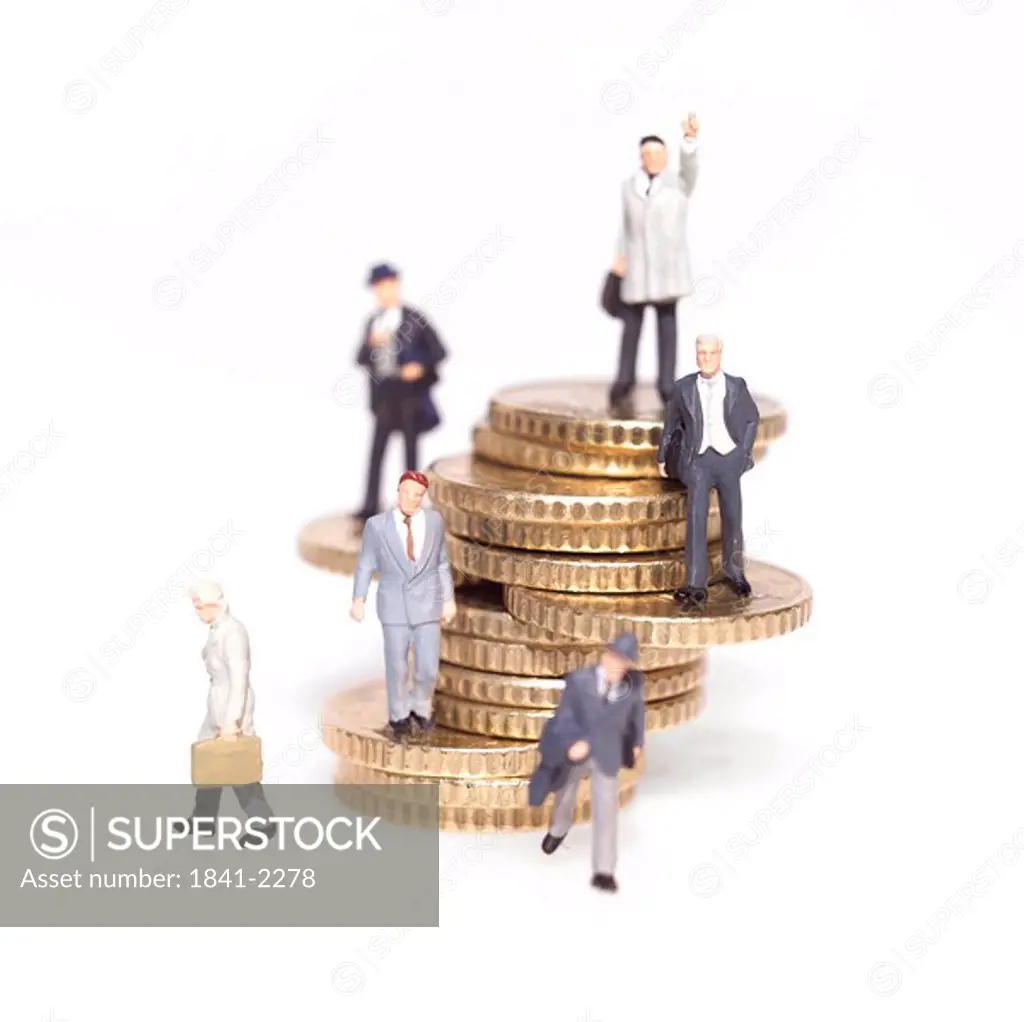 Figurines of businessmen with stack of coins