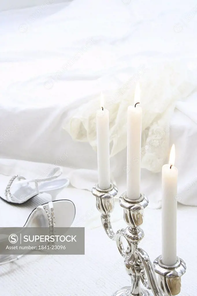 Close_up of lit candles with pair of high heels in background