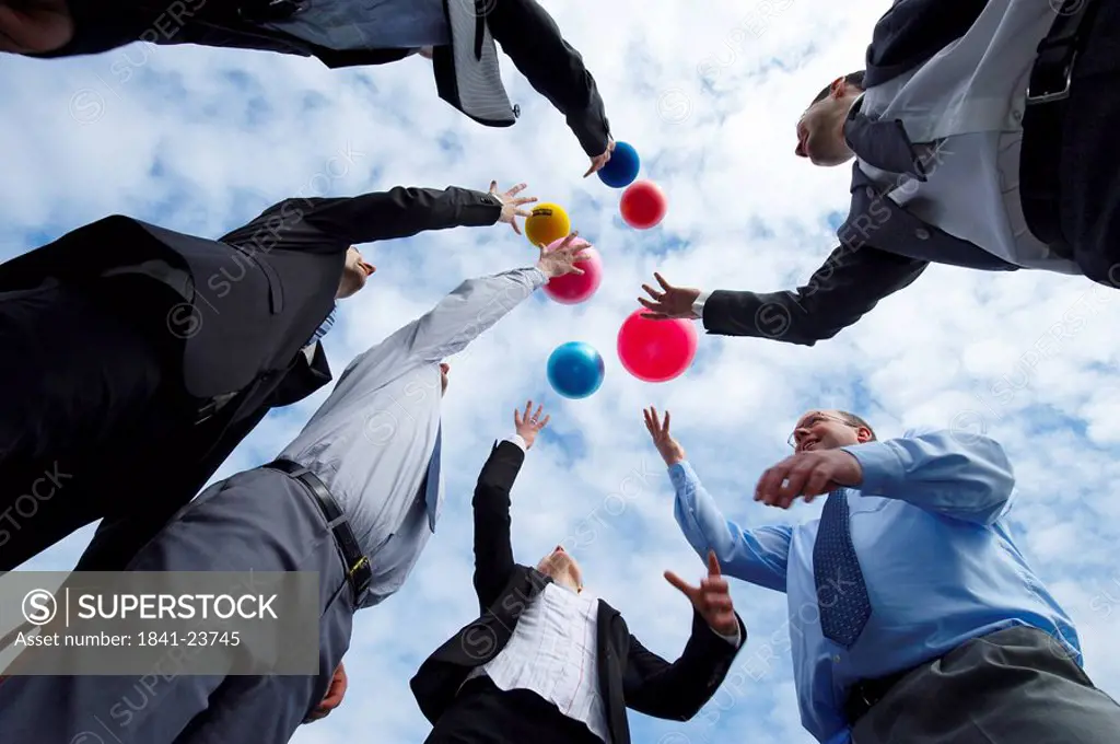 Low angle view of businesspeople throwing balls