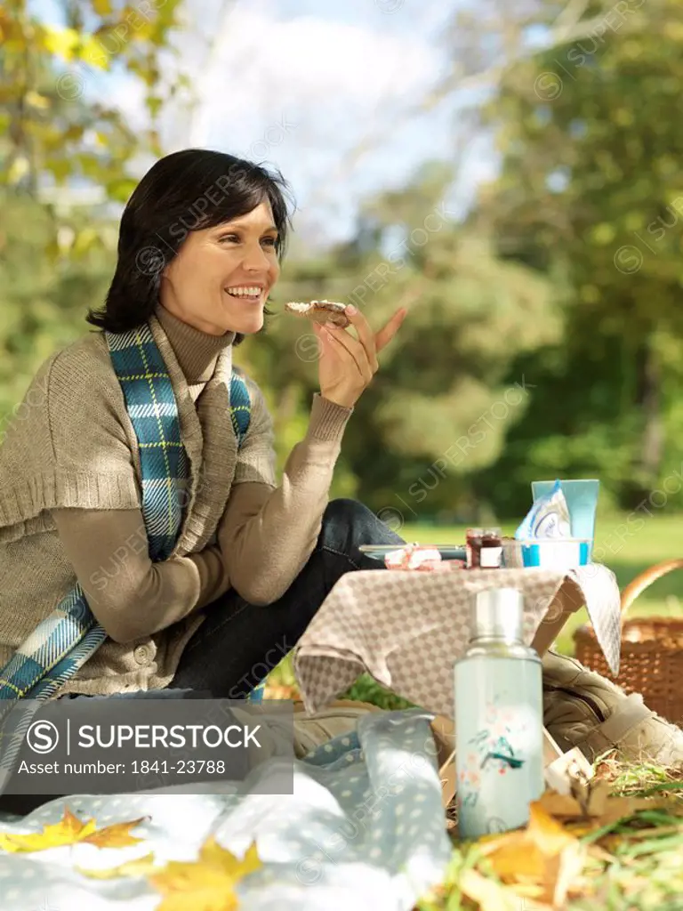 Side profile of mature woman eating a cheese slice in park