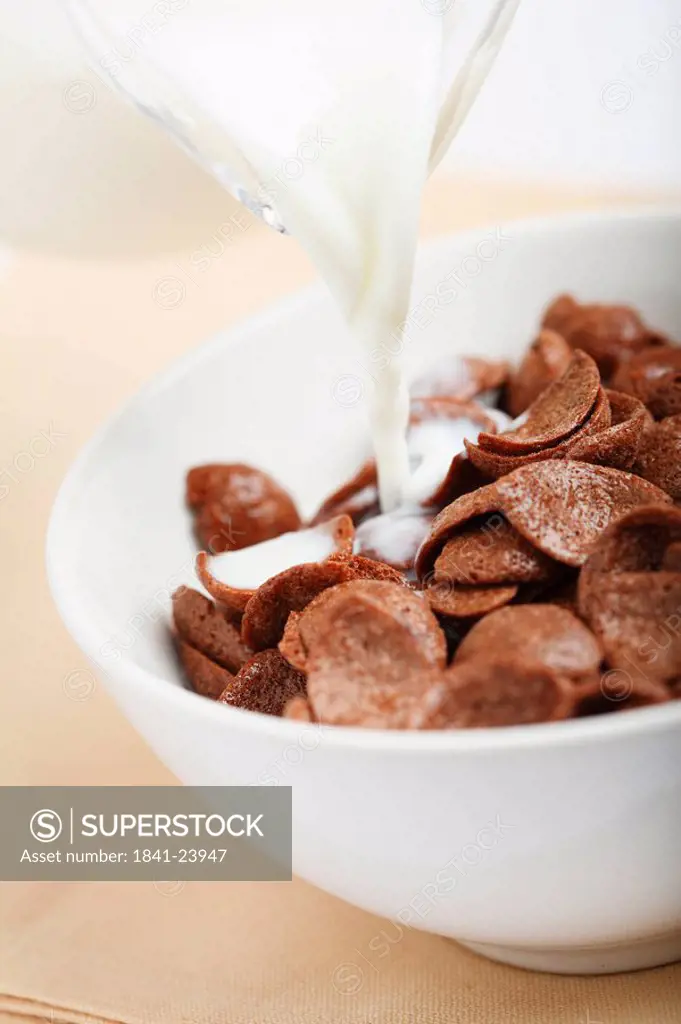 Milk pouring into a bowl with Cornflakes, close_up