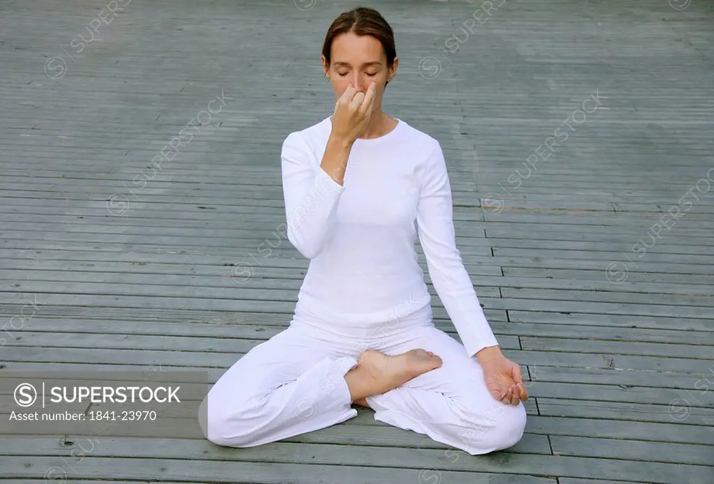 Woman sitting in lotus position on a deck, front view
