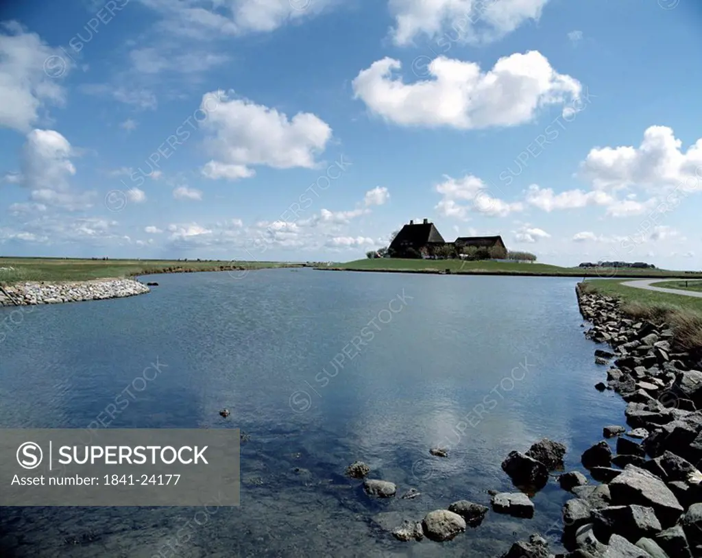 House on a lakeside under cloudy sky, Hallig, North Sea, Schleswig_Holstein, Germany