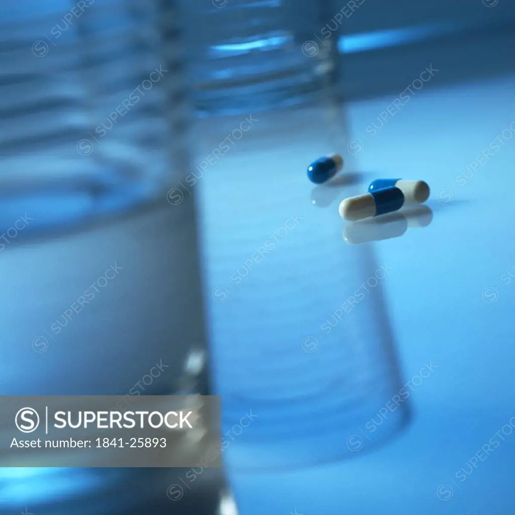 Close_up of capsules and glass of water