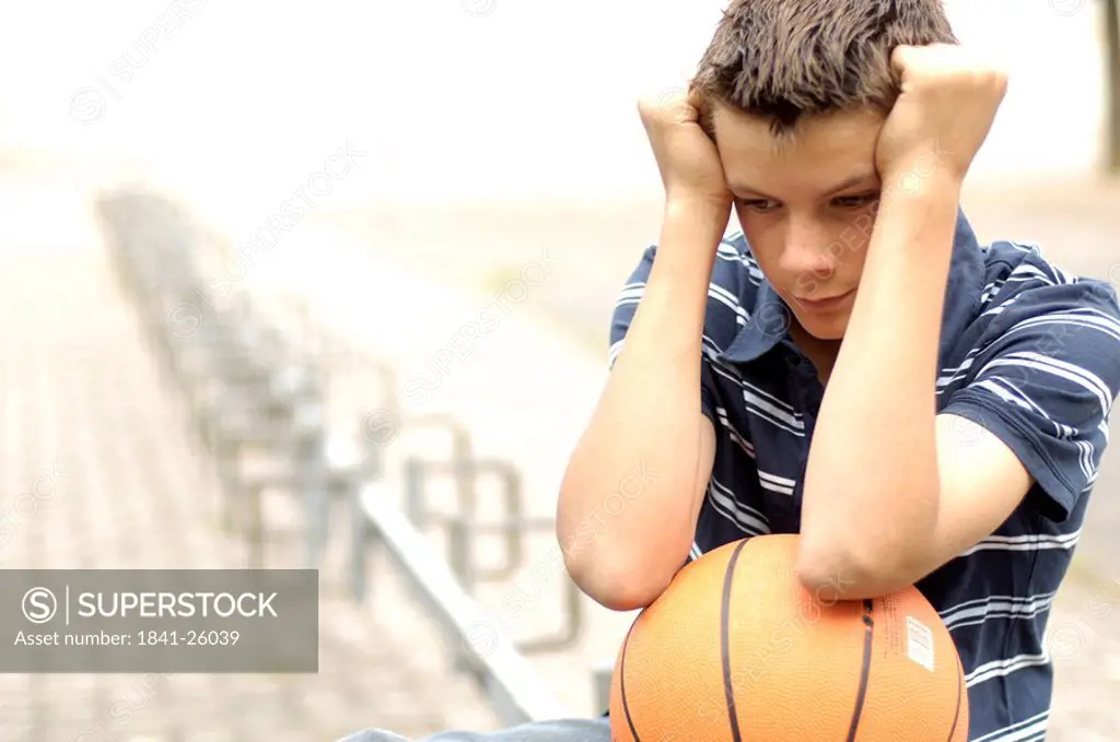 Close_up of teenage boy looking serious and holding basketball
