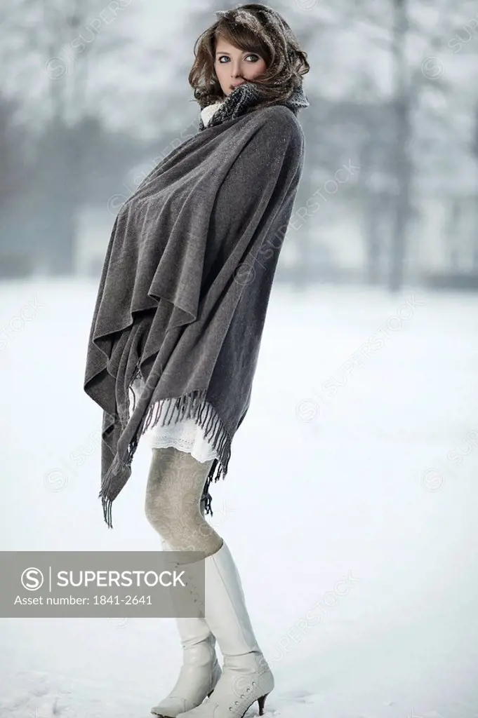 Young woman standing with poncho in snow