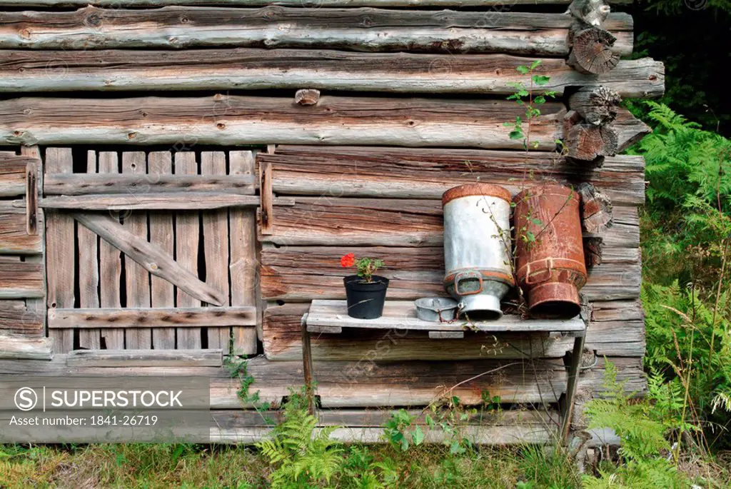 Milk churns in front of log cabin, Finland
