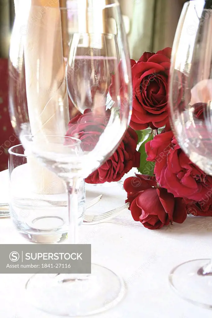 Stem glasses and bunch of roses on table