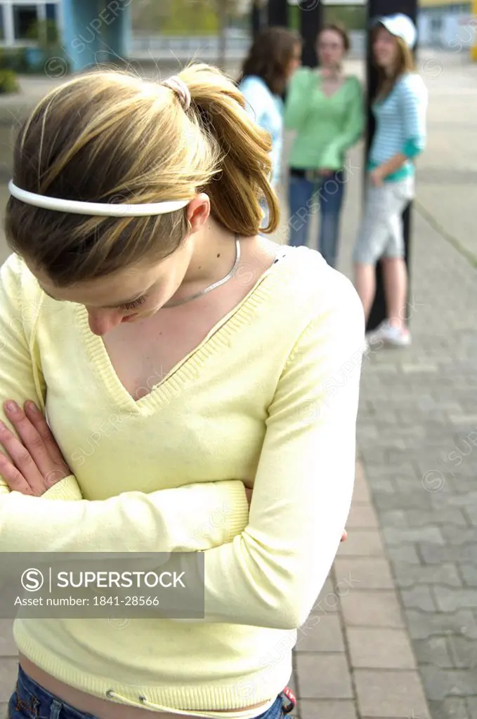 Close_up of teenage girl looking sad with her friends standing in background