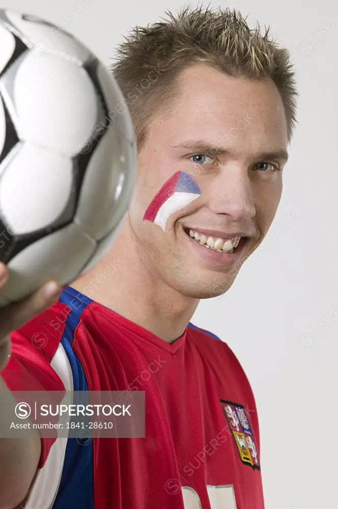 Portrait of male soccer fan holding soccer ball and smiling