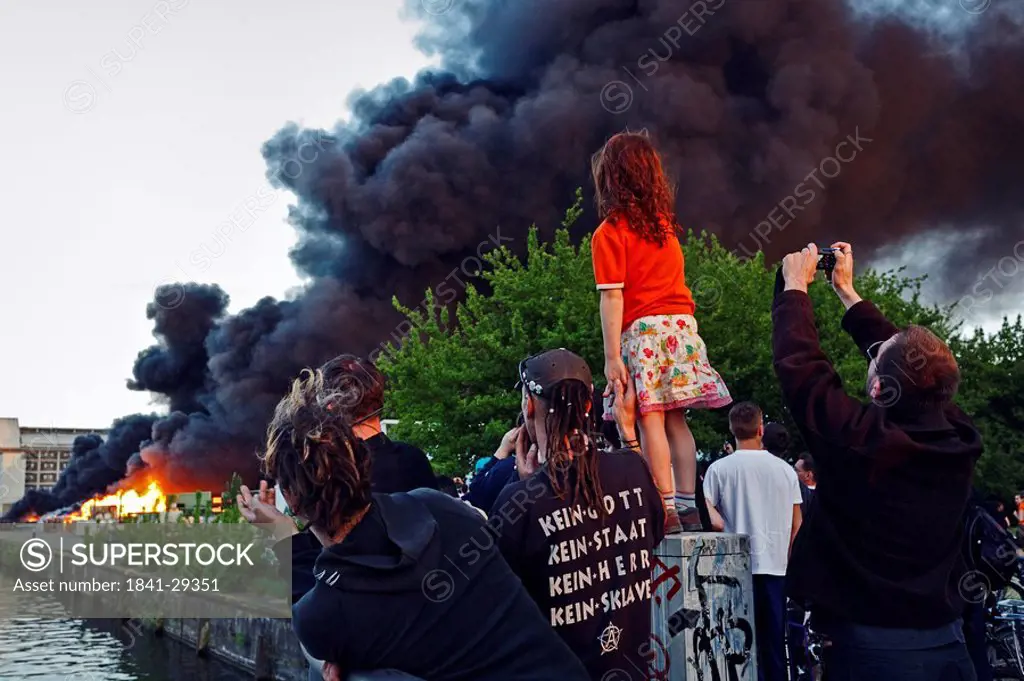 People looking at burning paper mill, Kreuzberg, Berlin, Germany