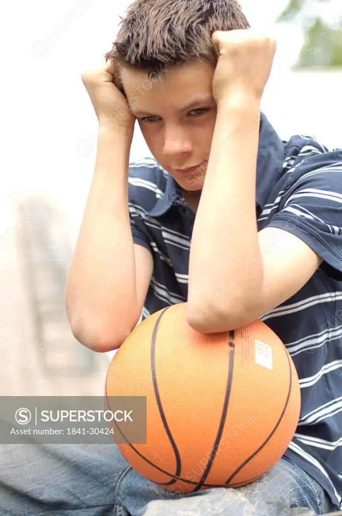Close_up of teenage boy looking serious and holding basketball