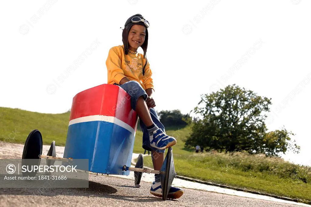 Portrait of boy sitting on soapbox and smiling