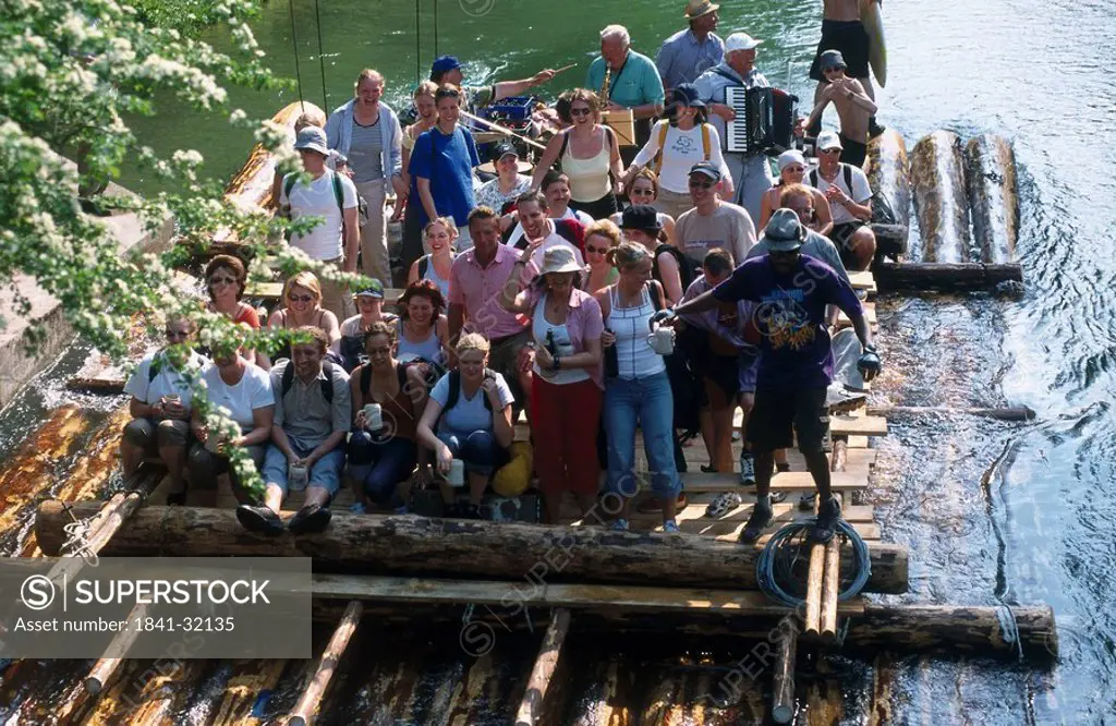 Group of tourists on wooden raft in river, River Isar, Munich, Bavaria, Germany