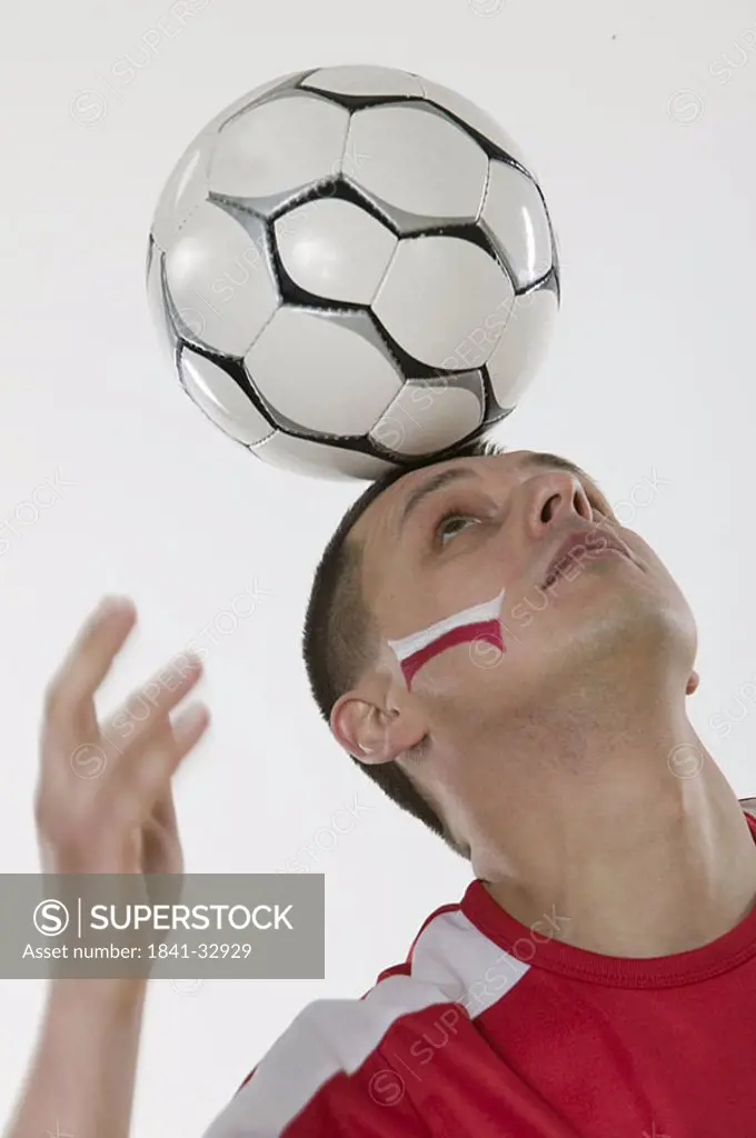 Close_up of man balancing soccer ball on his head