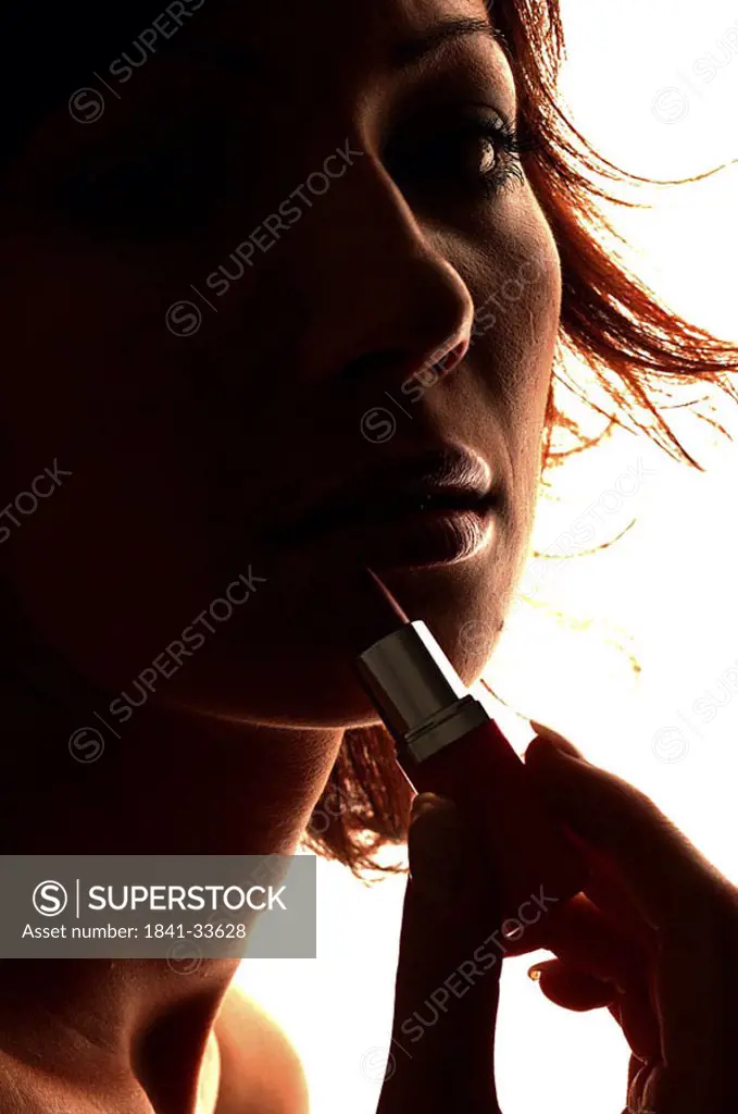 Young woman applying lipstick on lips