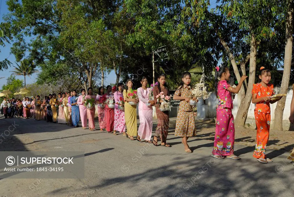 Group of women and girls walking in row with religious offerings, Nyaung Shwe, Inle Lake, Myanmar