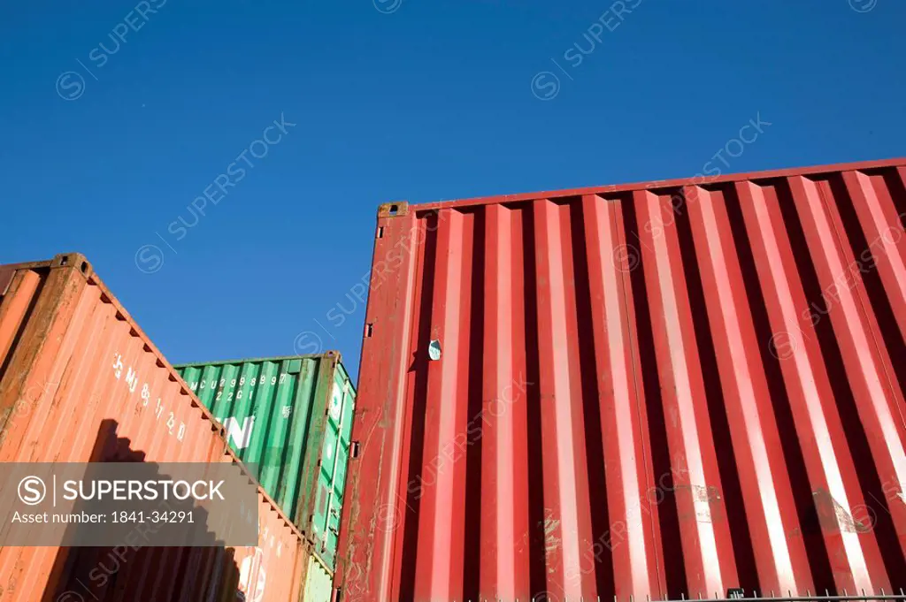 Low angle view of shipping cargo containers against blue sky