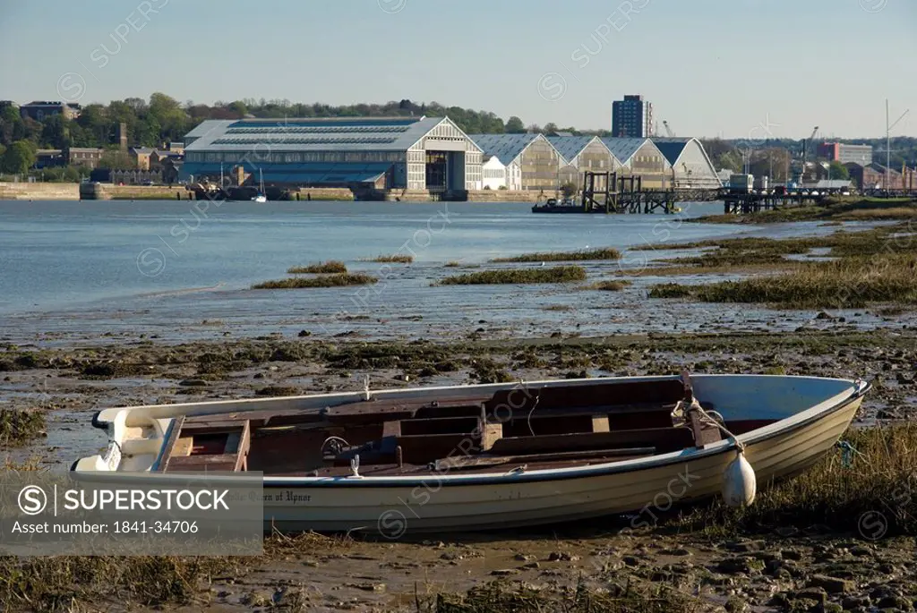 Boat on beach with buildings in background, Chatham, Medway, Kent, South East England, England