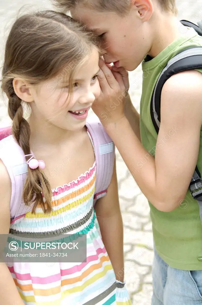 Close_up of boy whispering in girl´s ear