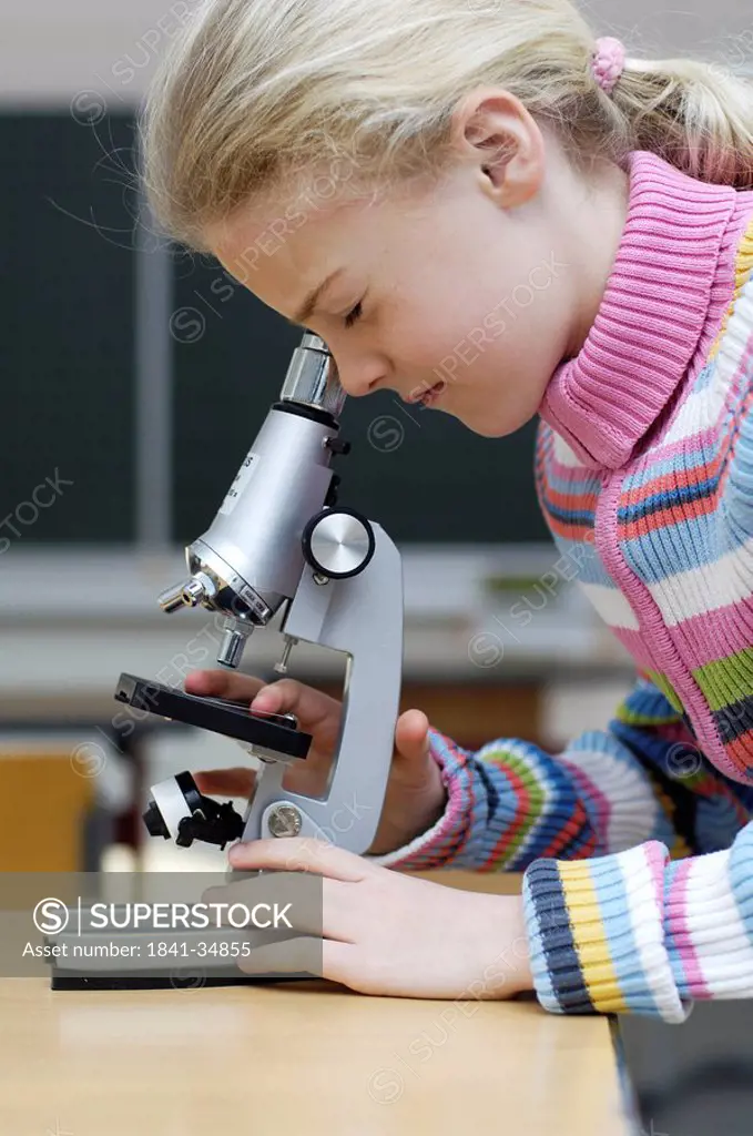 Side profile of girl looking through microscope