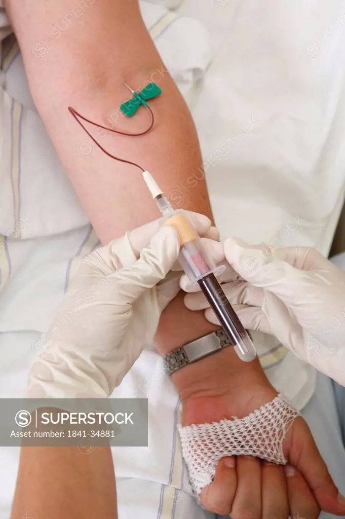 Close_up of person´s hands taking blood sample from patient´s arm