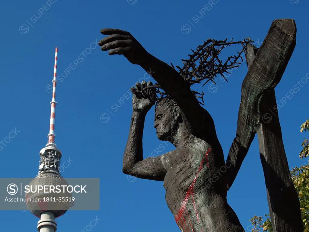 Low angle view of bronze statue with TV tower in background, Alexanderplatz, Berlin, Germany